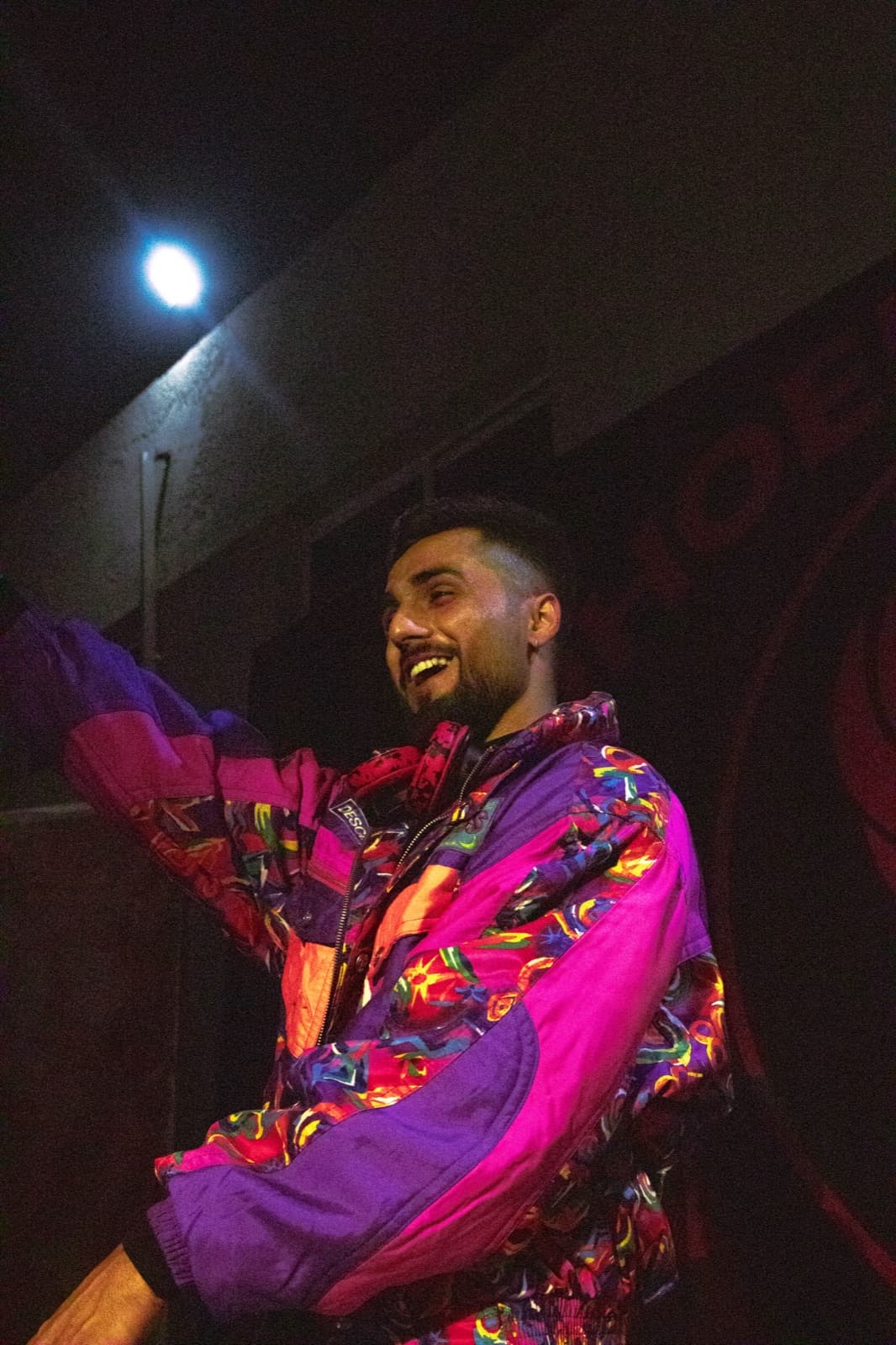 TOSHI laughing on stage in a vivid statement jacket