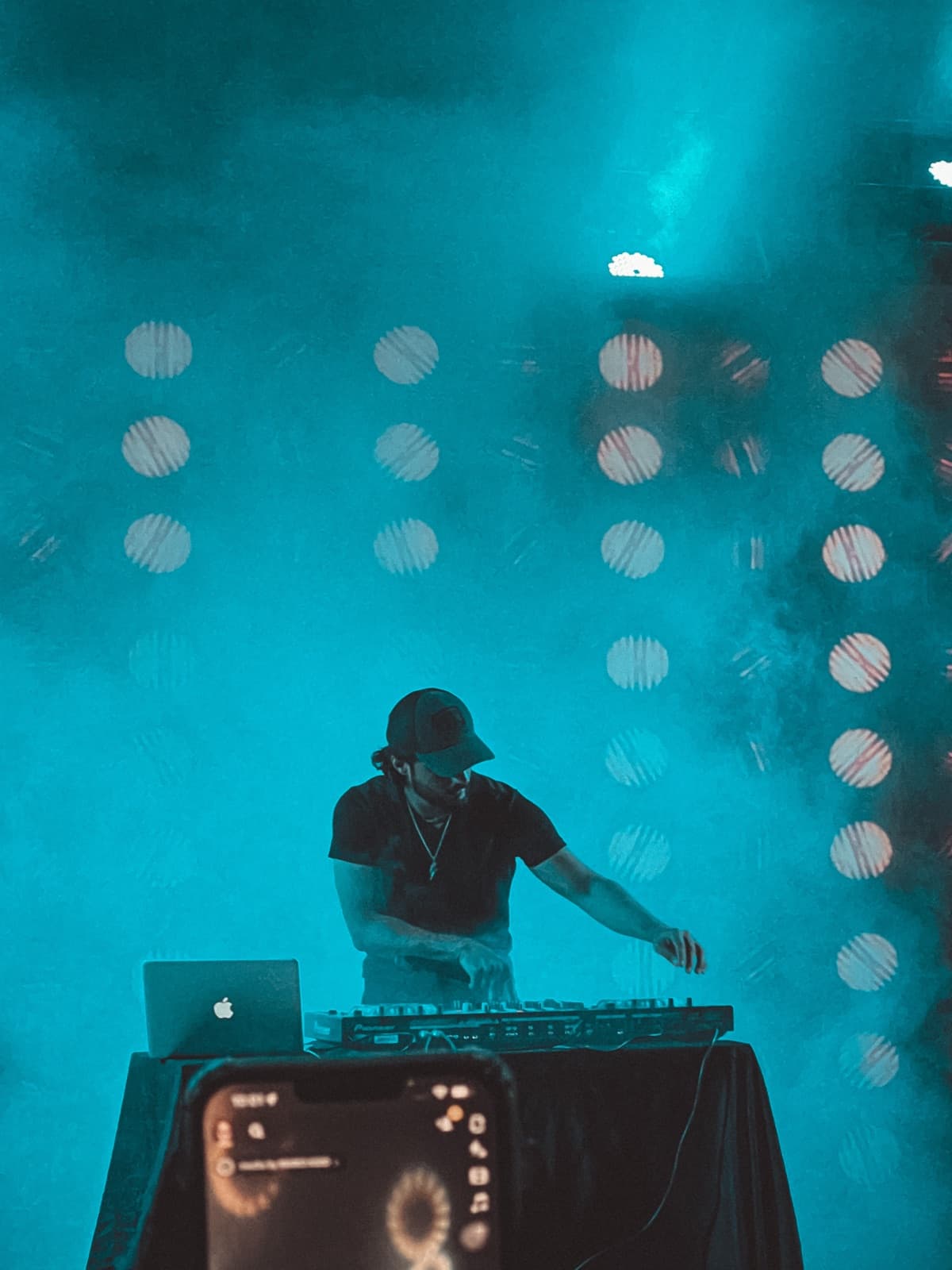TOSHI behind the decks bathed in blue light and smoke